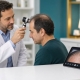 Fostoria News Doctor examines patient for hair restoration during consultation.